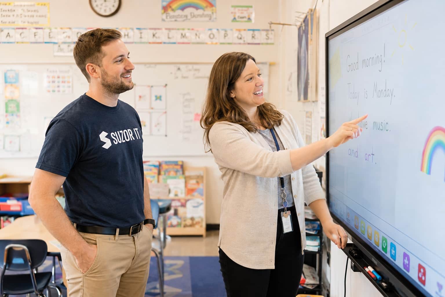 Teacher and Suzor IT technician at an interactive classroom display
